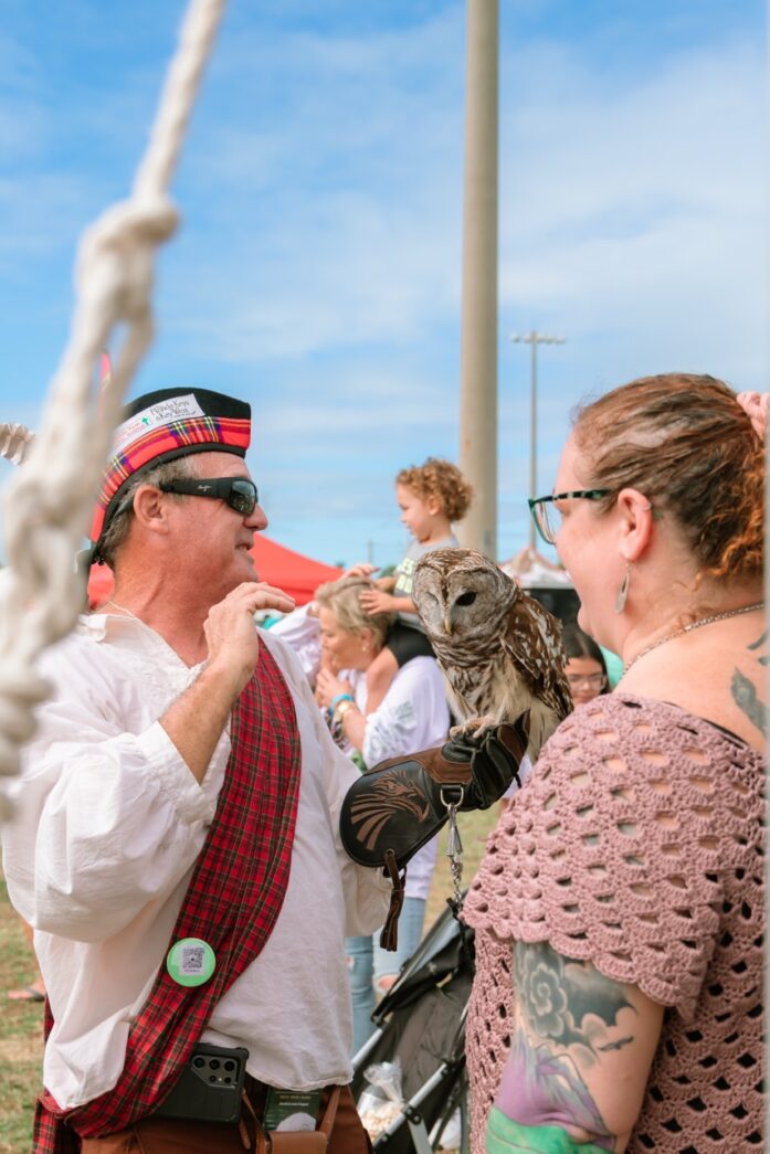 a man holding an owl while standing next to a woman