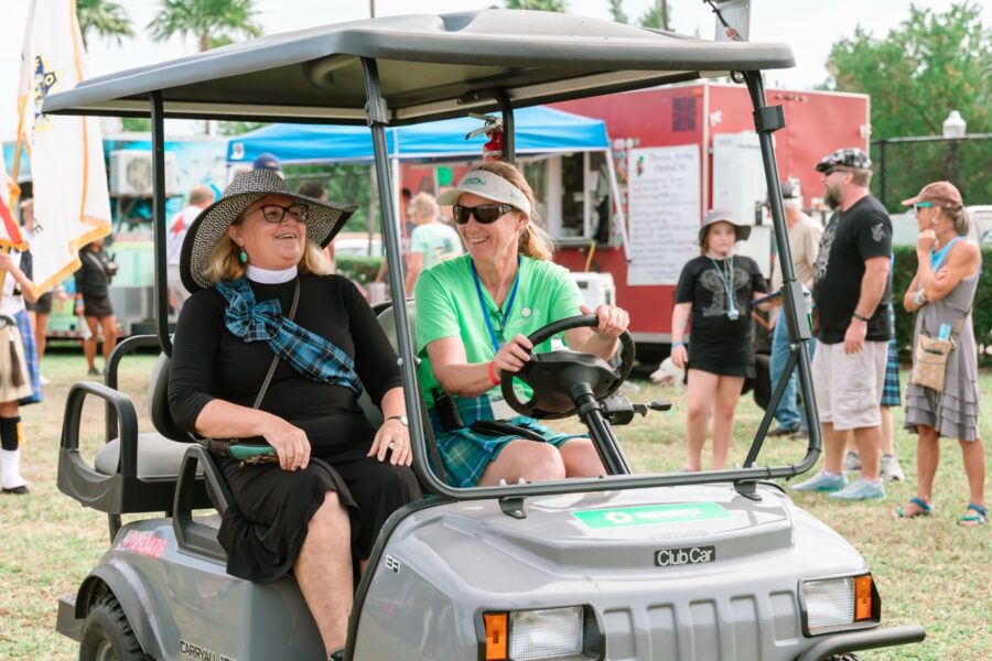 a couple of women riding on the back of a golf cart