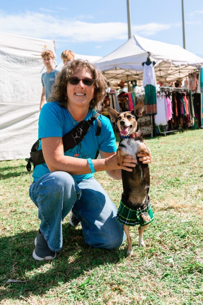 a woman kneeling down holding a small dog
