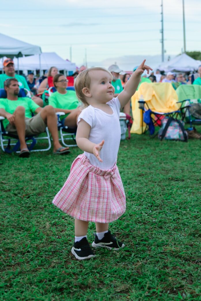 a little girl standing on top of a lush green field