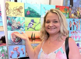 TRAVELING ART EXHIBIT FEATURING 150 UNIQUE CANVASES BEGINS IN KEY LARGO a woman standing in front of a wall of paintings