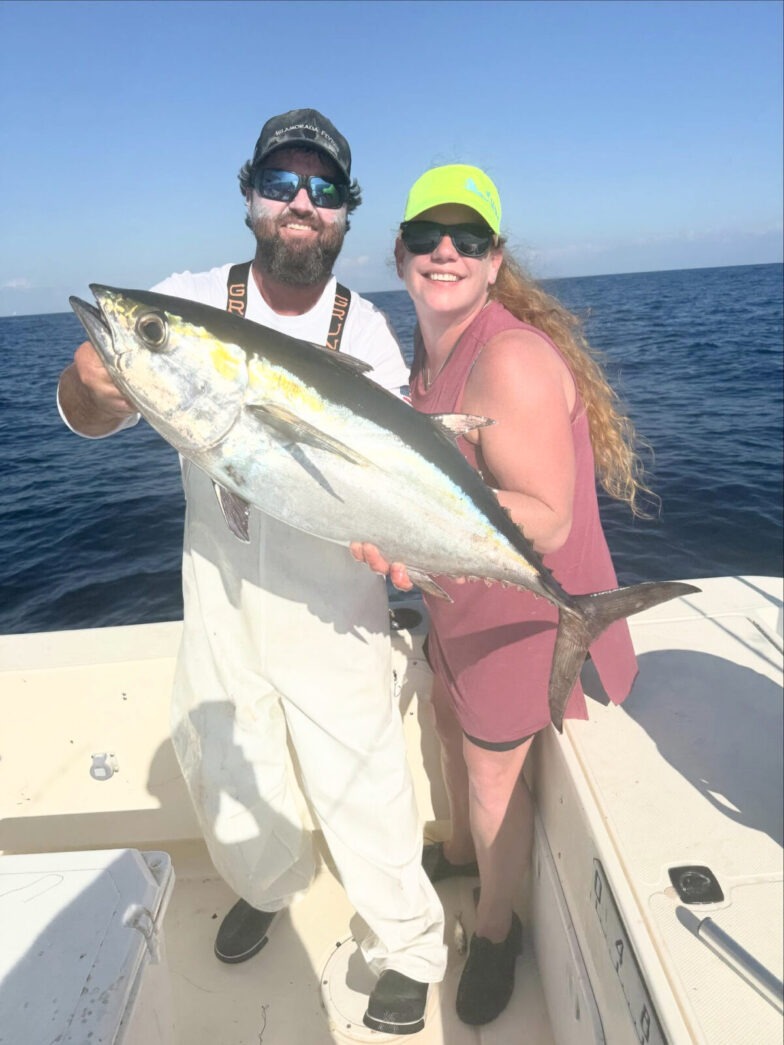 a man and a woman holding a fish on a boat