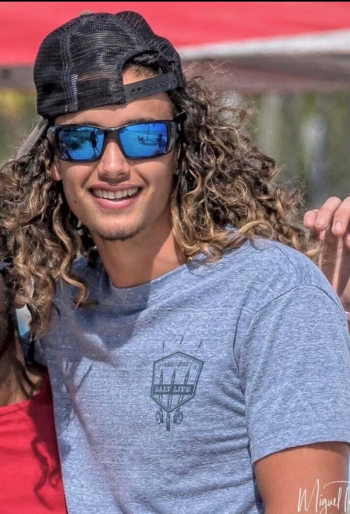 a man with long curly hair wearing sunglasses and a hat