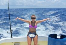 a woman standing on a boat holding a fish