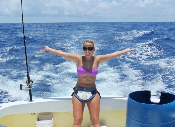 a woman standing on a boat holding a fish