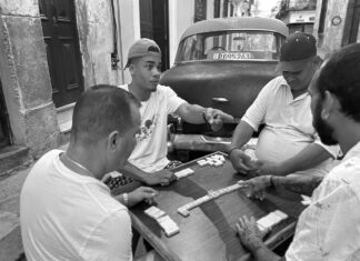 PHOTOGRAPHS CAPTURE CUBA AT GALLERY ON GREENE a group of men sitting around a table playing a game