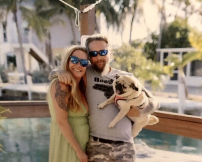 a man and a woman pose for a picture with a dog