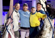 a group of men standing next to a large fish