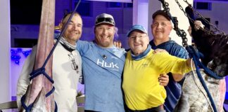 a group of men standing next to a large fish