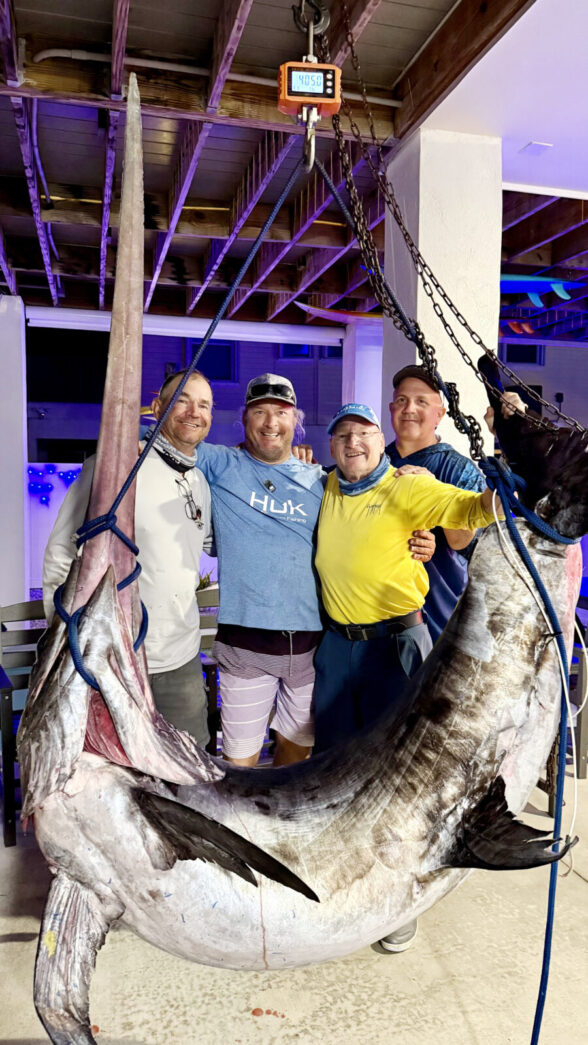 a group of people standing around a large fish