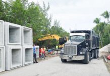a large truck driving down a road next to a construction site