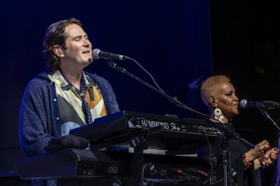 a man standing next to a keyboard on a stage