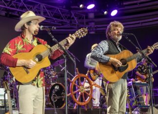 IN PICTURES: JIMMY BUFFETT’S CORAL REEFER BAND KEEPS THE PARTY GOING two men are playing guitars and singing on stage