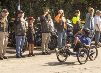 HEALING WHEELS: WOUNDED WARRIORS COMPLETE ANNUAL SOLDIER RIDE DOWN OVERSEAS HIGHWAY a group of people standing around a man on a bike