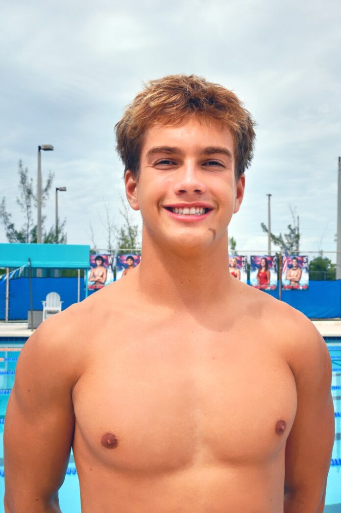 a young man standing in front of a swimming pool