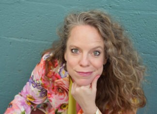 RED BARN THEATRE WILL SEE YOU ‘AT THE WEDDING’ a woman sitting at a table with a glass of wine