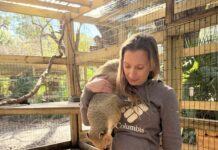 a woman holding a small animal inside of a cage