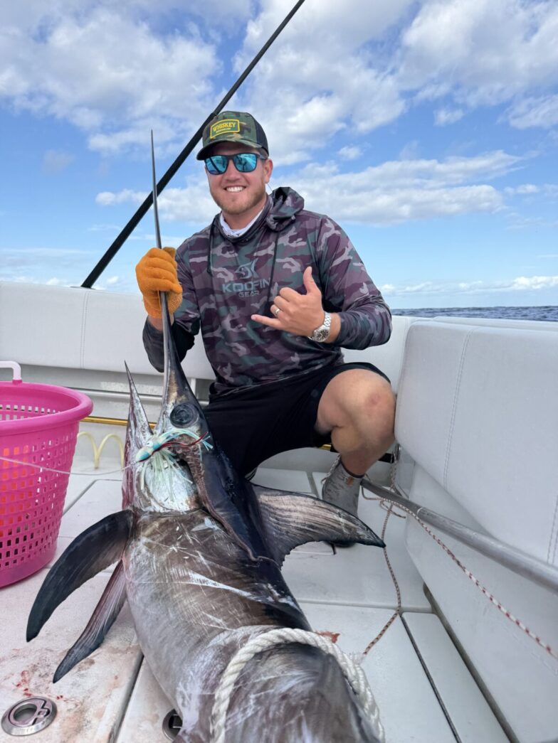 a man sitting on a boat holding a fish