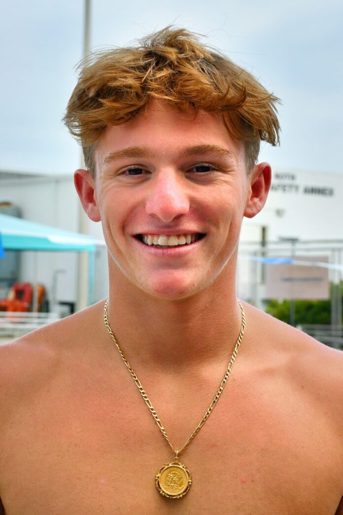 a man wearing a necklace with a medallion on it