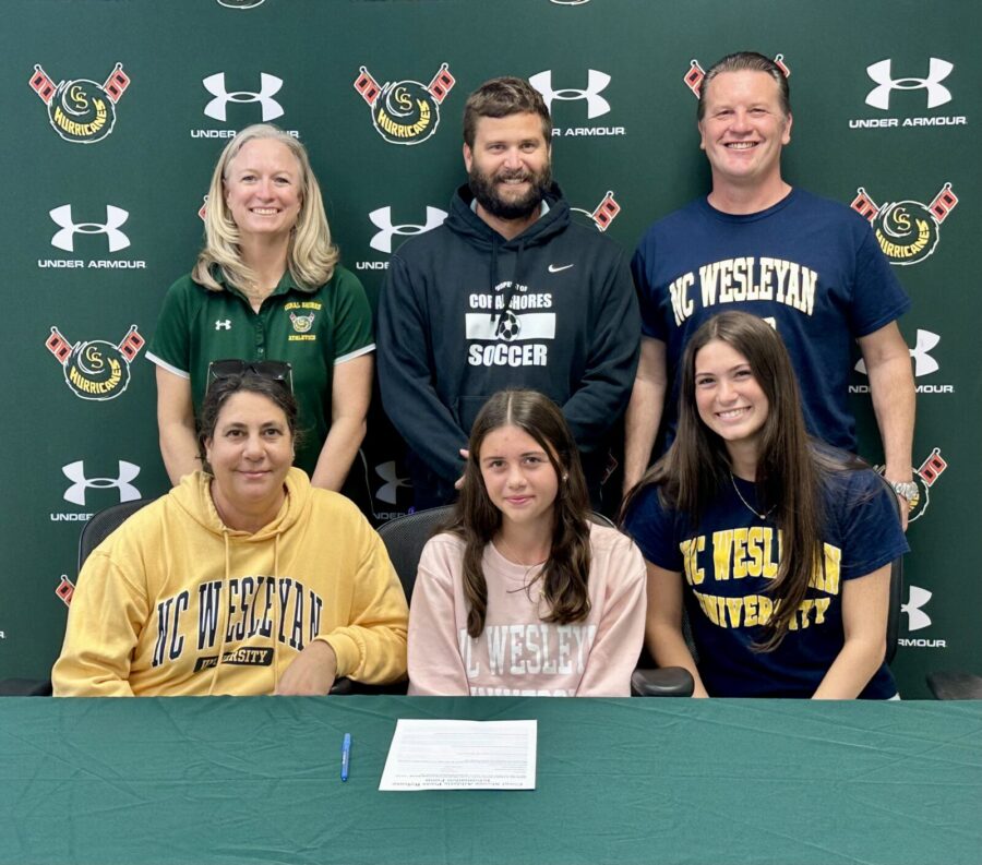a group of people standing in front of a green wall