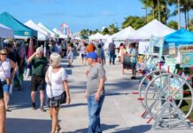 a group of people walking down a sidewalk next to tents