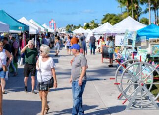 THURSDAY FARMERS MARKET AT TRUMAN WATERFRONT IN KEY WEST MOVES UP AN HOUR a group of people walking down a sidewalk next to tents