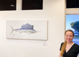 a woman sitting at a table in front of a painting